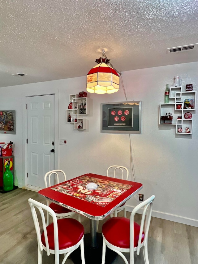 dining space with a textured ceiling and hardwood / wood-style flooring