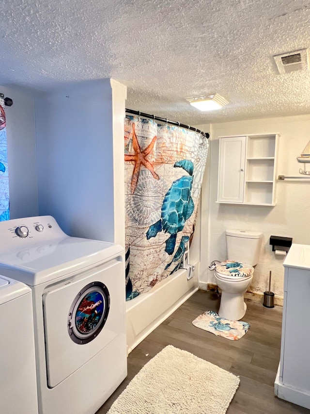 washroom featuring dark hardwood / wood-style flooring, a textured ceiling, and washer and clothes dryer