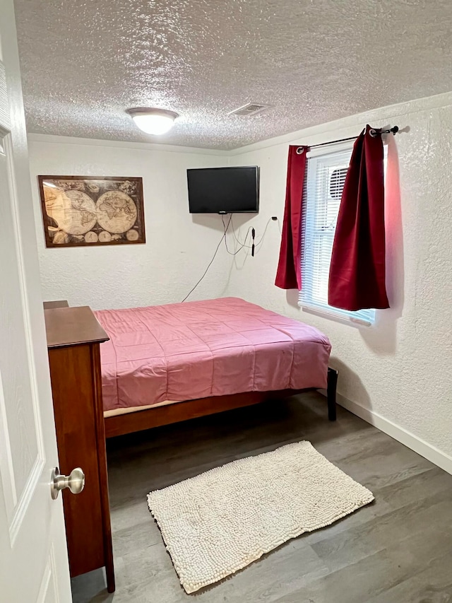 bedroom featuring a textured ceiling and hardwood / wood-style flooring