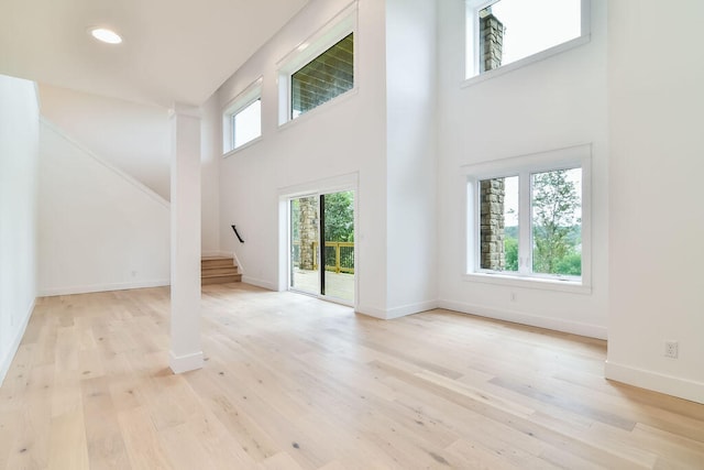 unfurnished living room featuring light hardwood / wood-style flooring and a high ceiling