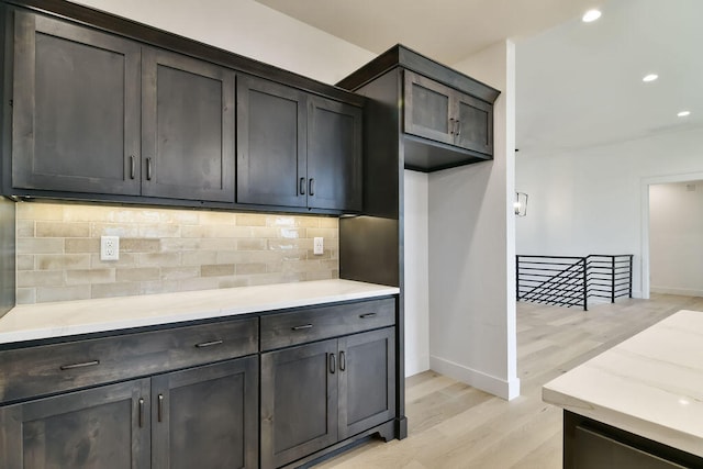 kitchen with dark brown cabinets, light hardwood / wood-style flooring, and tasteful backsplash