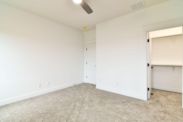 unfurnished bedroom with ceiling fan, light colored carpet, a closet, and a spacious closet