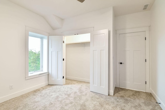 unfurnished bedroom with light carpet, a closet, and vaulted ceiling