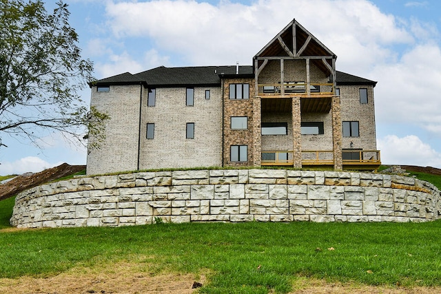 rear view of property featuring a balcony and a lawn