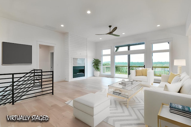 living room featuring a fireplace, light hardwood / wood-style floors, and ceiling fan