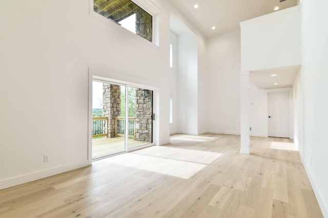 interior space with a towering ceiling and light hardwood / wood-style floors