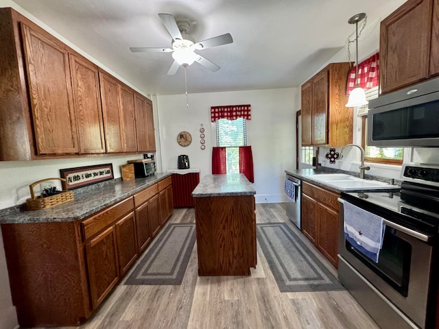 kitchen with sink, hanging light fixtures, hardwood / wood-style flooring, appliances with stainless steel finishes, and a kitchen island