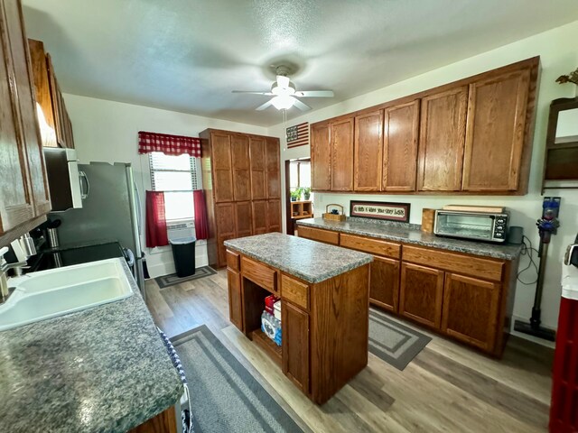 kitchen with light hardwood / wood-style flooring, a kitchen island, ceiling fan, and sink