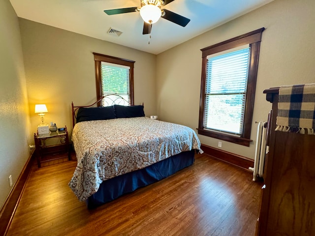 bedroom featuring dark hardwood / wood-style flooring, multiple windows, and ceiling fan