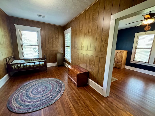 living area featuring wooden walls, radiator, and dark wood-type flooring