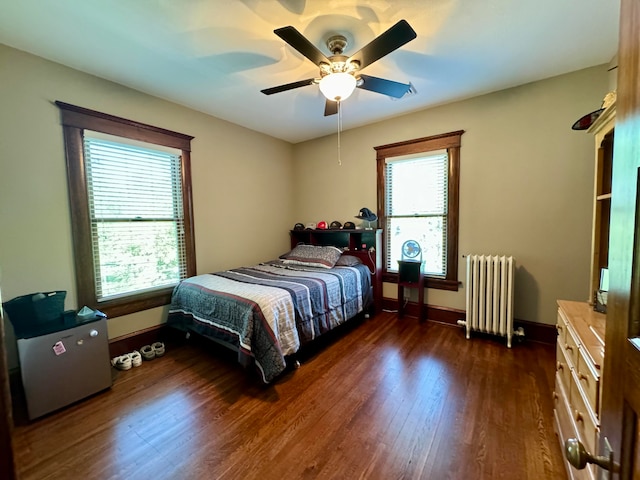 bedroom featuring radiator, ceiling fan, dark wood-type flooring, and multiple windows