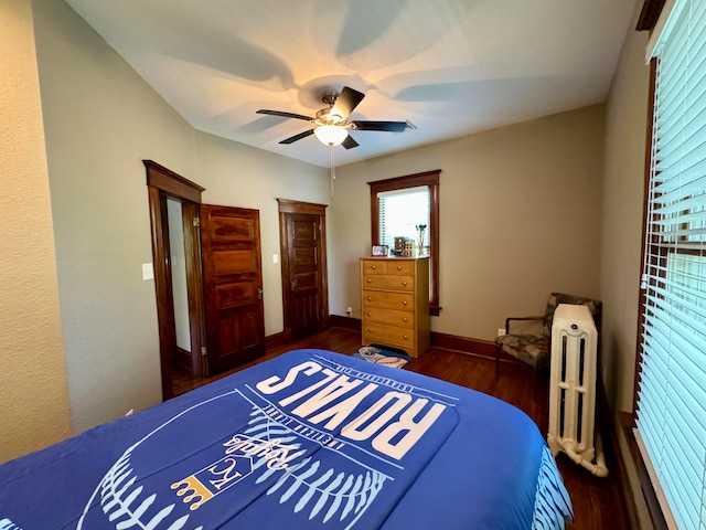 bedroom featuring ceiling fan, radiator heating unit, and dark wood-type flooring