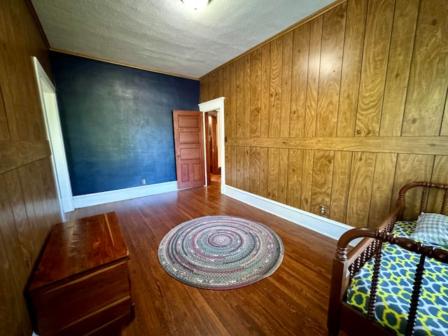 bedroom featuring wooden walls, dark wood-type flooring, and a textured ceiling