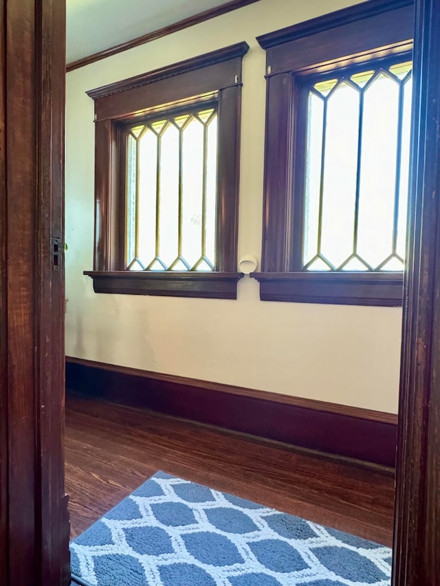 interior space featuring dark wood-type flooring, a healthy amount of sunlight, and ornamental molding