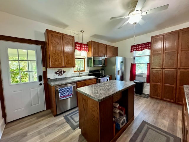 kitchen featuring pendant lighting, sink, light hardwood / wood-style floors, appliances with stainless steel finishes, and a kitchen island