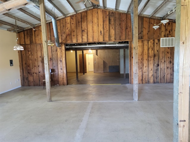 garage featuring ceiling fan and wood walls