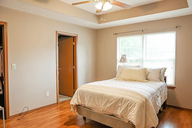 bedroom featuring ceiling fan, a tray ceiling, and hardwood / wood-style floors