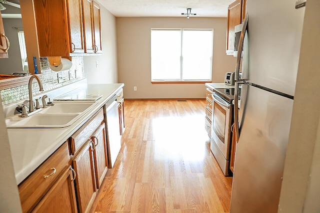 kitchen with light wood-type flooring, sink, stainless steel appliances, and a textured ceiling