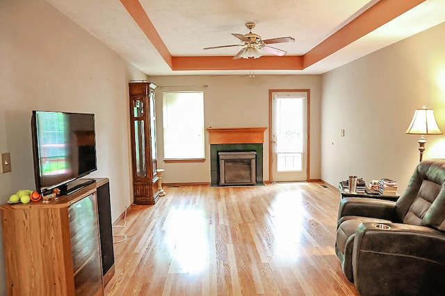 living room featuring ceiling fan, light hardwood / wood-style flooring, and a raised ceiling