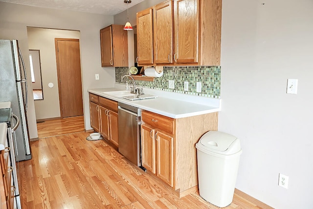 kitchen with sink, tasteful backsplash, decorative light fixtures, stainless steel appliances, and light hardwood / wood-style floors