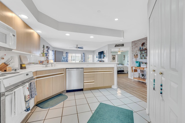 kitchen featuring light hardwood / wood-style floors, ceiling fan, white appliances, light brown cabinetry, and kitchen peninsula