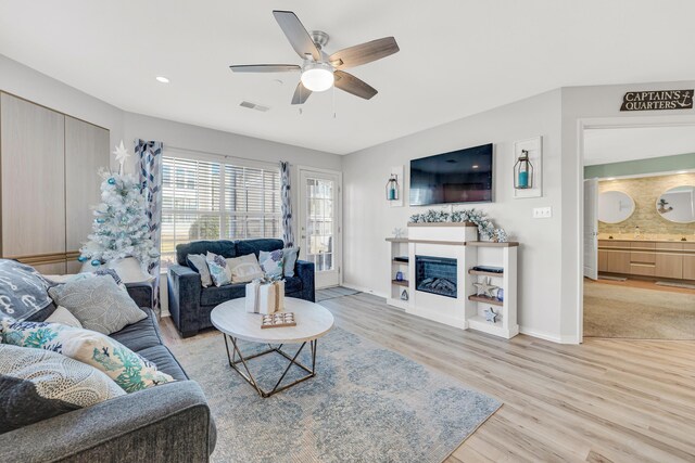 215 Meadow Brook Ln Unit 1, Branson, MO 65616 - living area featuring visible vents, a glass covered fireplace, baseboards, a ceiling fan, and wood finished floors
