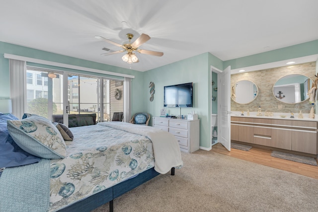 bedroom featuring ensuite bathroom, ceiling fan, light carpet, and sink