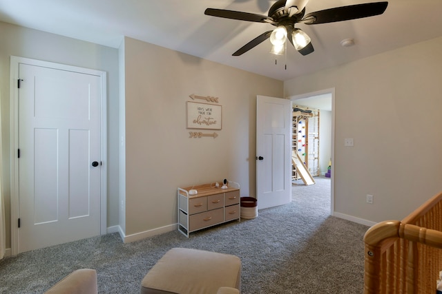 carpeted bedroom with ceiling fan and a crib