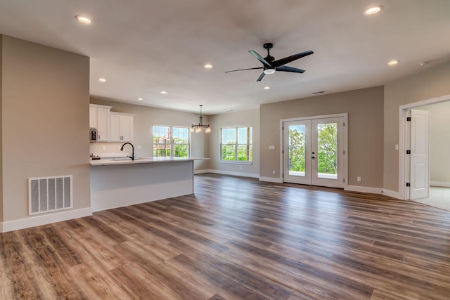 unfurnished living room with ceiling fan with notable chandelier, dark hardwood / wood-style flooring, and sink