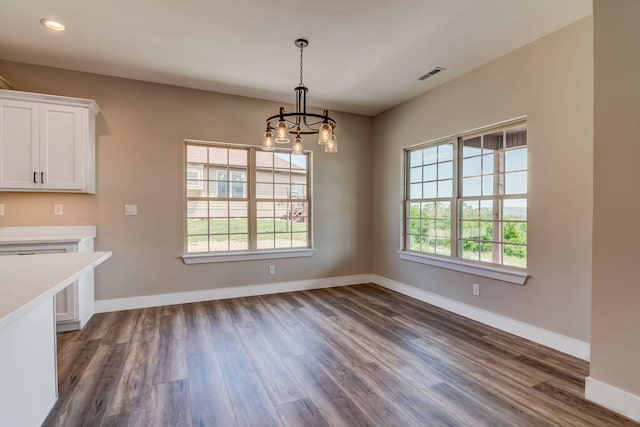 unfurnished dining area with a notable chandelier, dark wood-type flooring, and a wealth of natural light