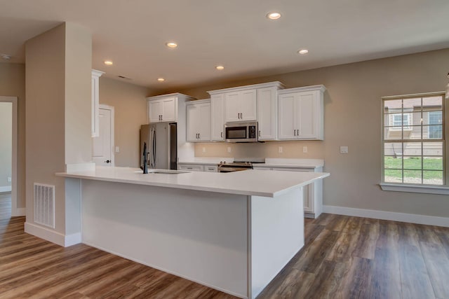 kitchen with dark hardwood / wood-style floors, appliances with stainless steel finishes, sink, and white cabinetry