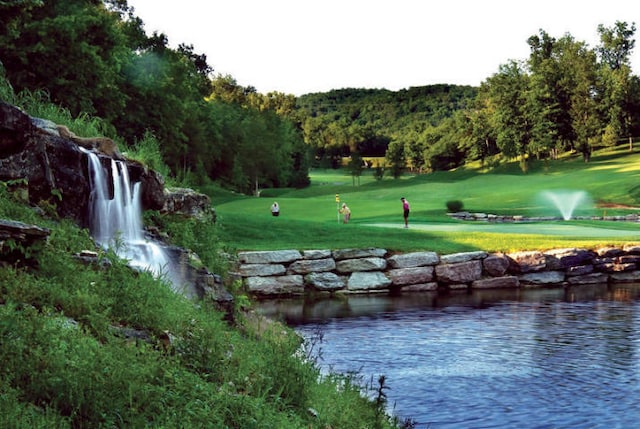 view of property's community with a water view and a lawn