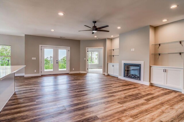 162 Mountain View Cir, Branson West, MO 65737 - unfurnished living room with a glass covered fireplace, wood finished floors, a ceiling fan, and french doors