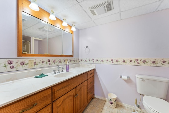 bathroom with vanity, a drop ceiling, tile patterned floors, toilet, and a shower