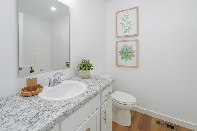 bathroom with toilet, baseboards, visible vents, wood finished floors, and vanity