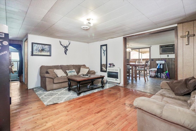 living room featuring wood-type flooring, heating unit, and a wall mounted AC