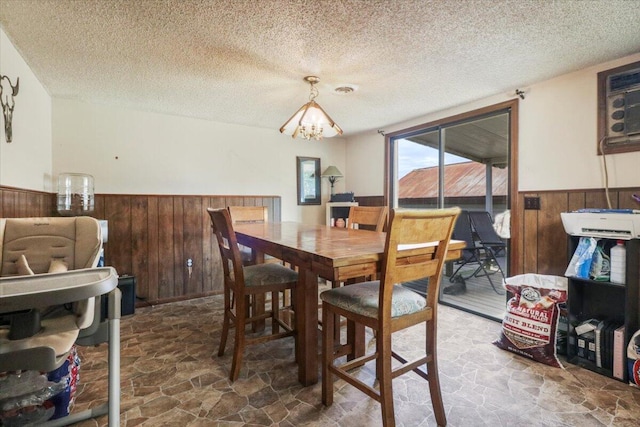 dining room with wood walls, a chandelier, and a textured ceiling