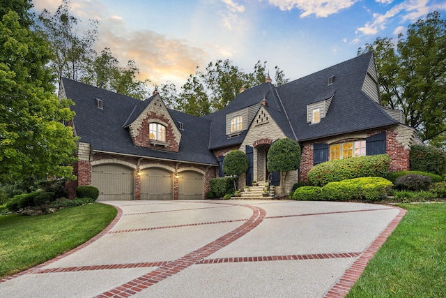 french country style house with driveway, a yard, and a garage