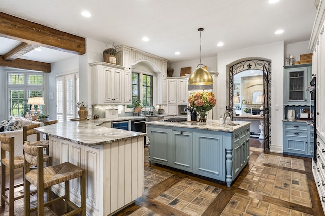 kitchen with an island with sink, kitchen peninsula, hanging light fixtures, and a kitchen breakfast bar