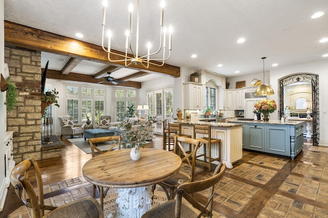 dining space with beamed ceiling, ceiling fan with notable chandelier, and a textured ceiling