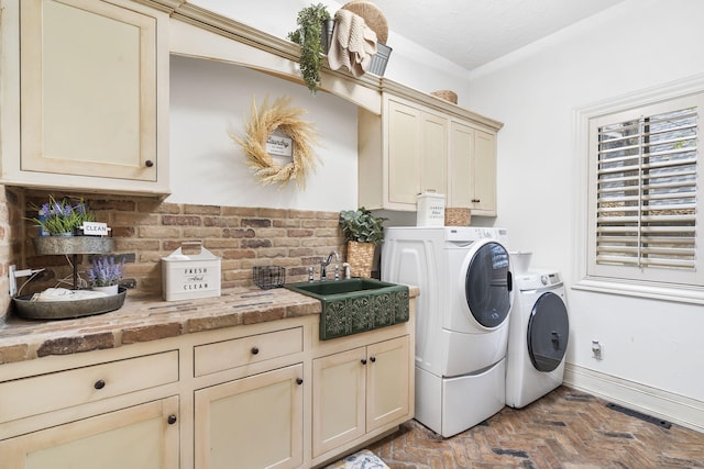 clothes washing area with visible vents, a sink, baseboards, washer and dryer, and cabinet space