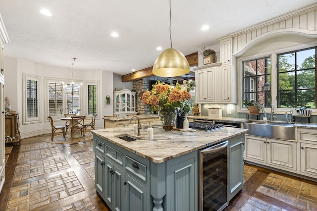 kitchen featuring recessed lighting, beverage cooler, cream cabinets, and a sink
