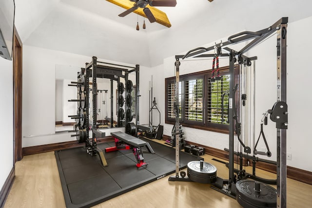 exercise room with wood finished floors, a ceiling fan, and baseboards