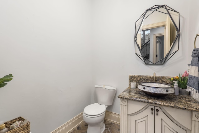 bathroom with baseboards, toilet, and vanity