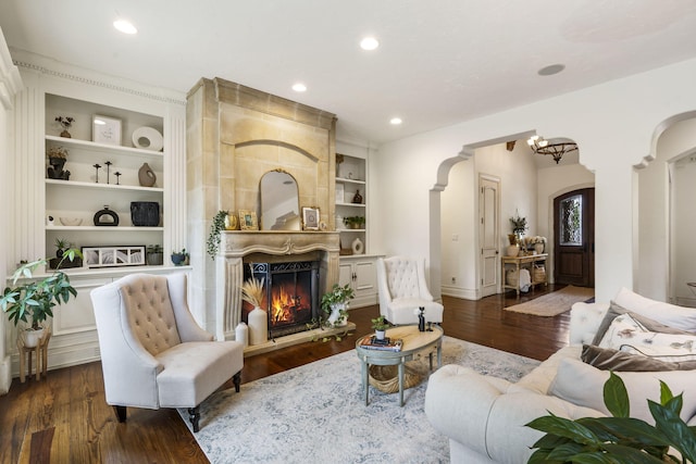 sitting room with dark wood-type flooring, built in features, and a large fireplace