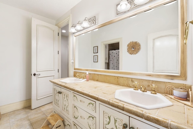 bathroom with tile patterned floors, baseboards, a sink, and double vanity