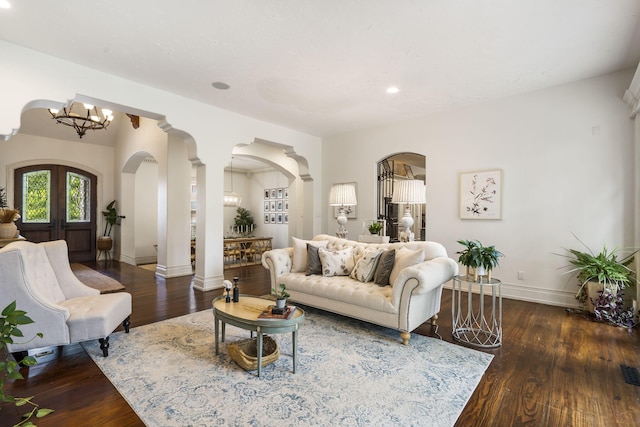 living room with decorative columns, french doors, an inviting chandelier, and dark hardwood / wood-style flooring