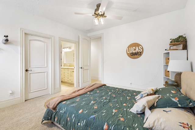 carpeted bedroom featuring ensuite bath, a ceiling fan, and baseboards