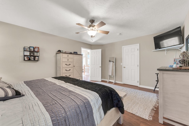 bedroom with ceiling fan, hardwood / wood-style flooring, and a textured ceiling