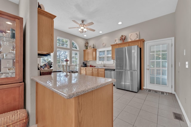 kitchen with light stone countertops, light brown cabinets, appliances with stainless steel finishes, and ceiling fan